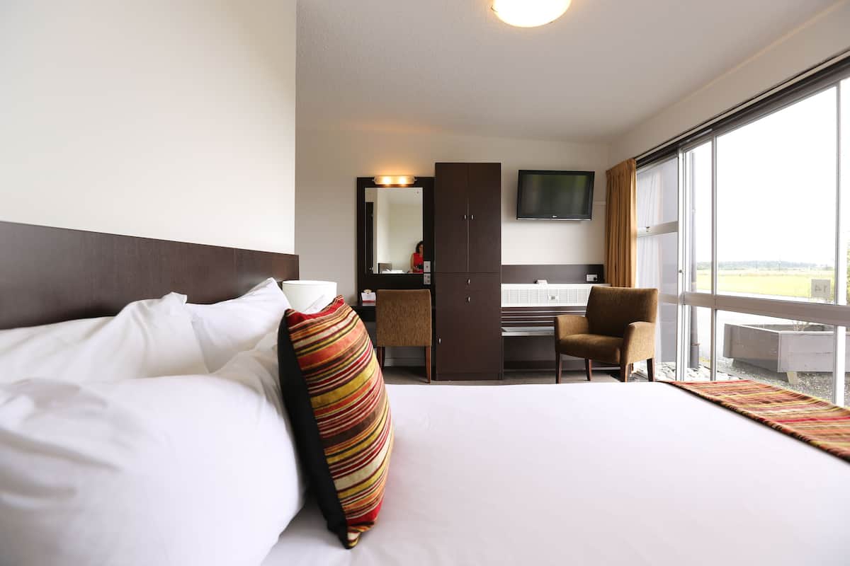 A hotel room with a bed, a desk, a chair, a television, and a large window.