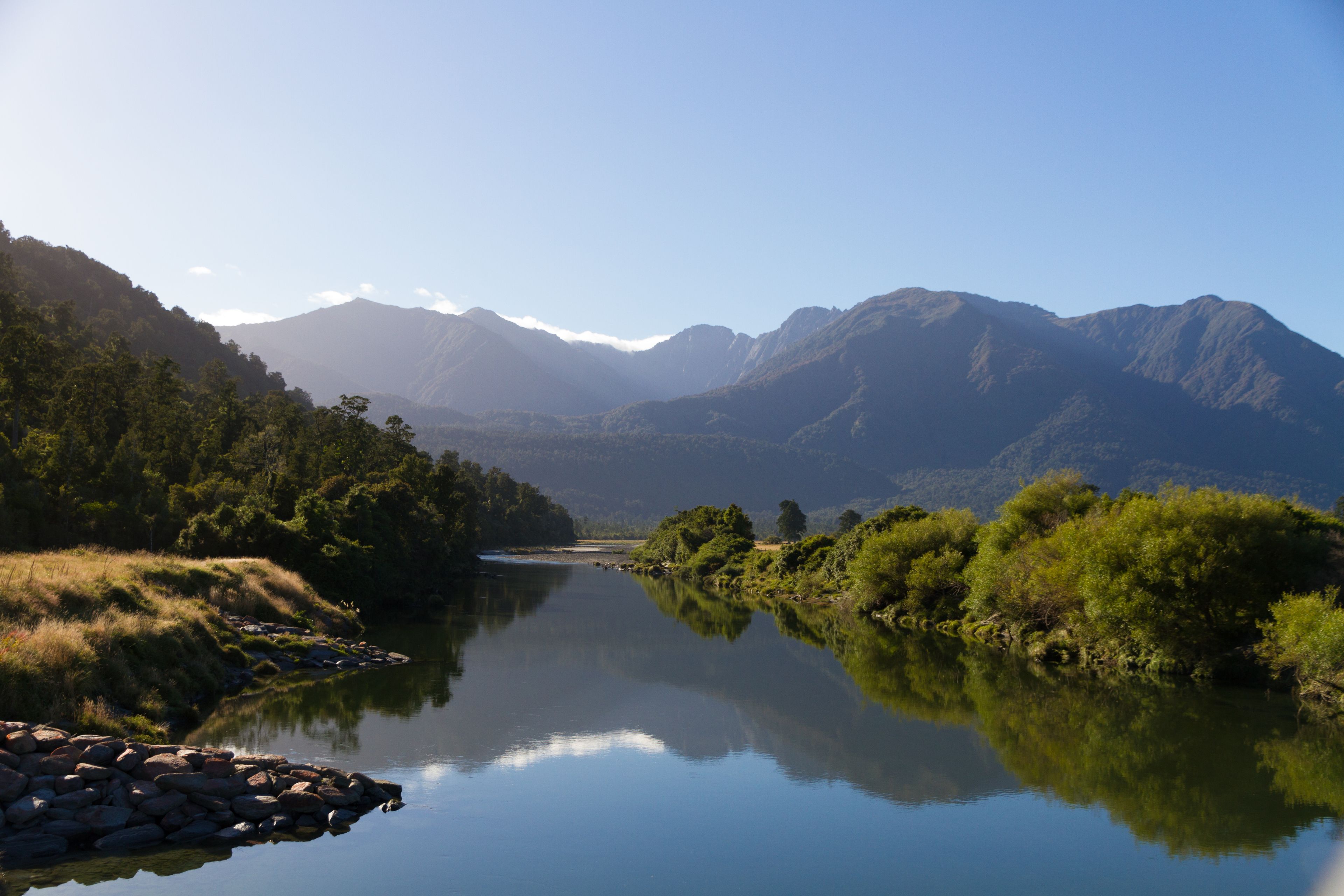 A calm river with mountains in the background.