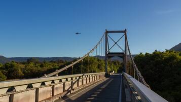 A suspension bridge with a clear view of the landscape and a helicopter in the distance.