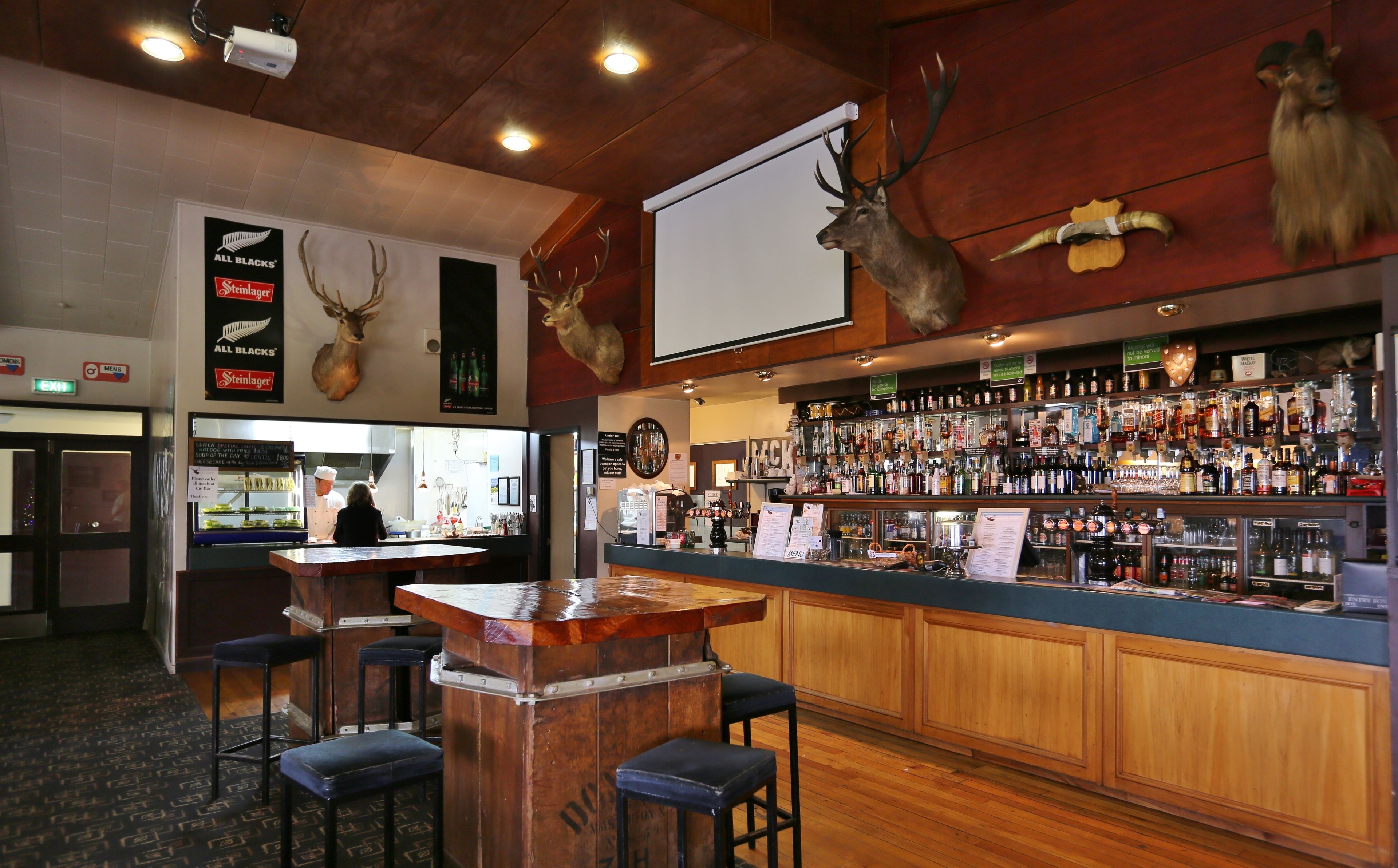 Una zona de bar con taburetes de madera, una barra y una variedad de botellas de licor.