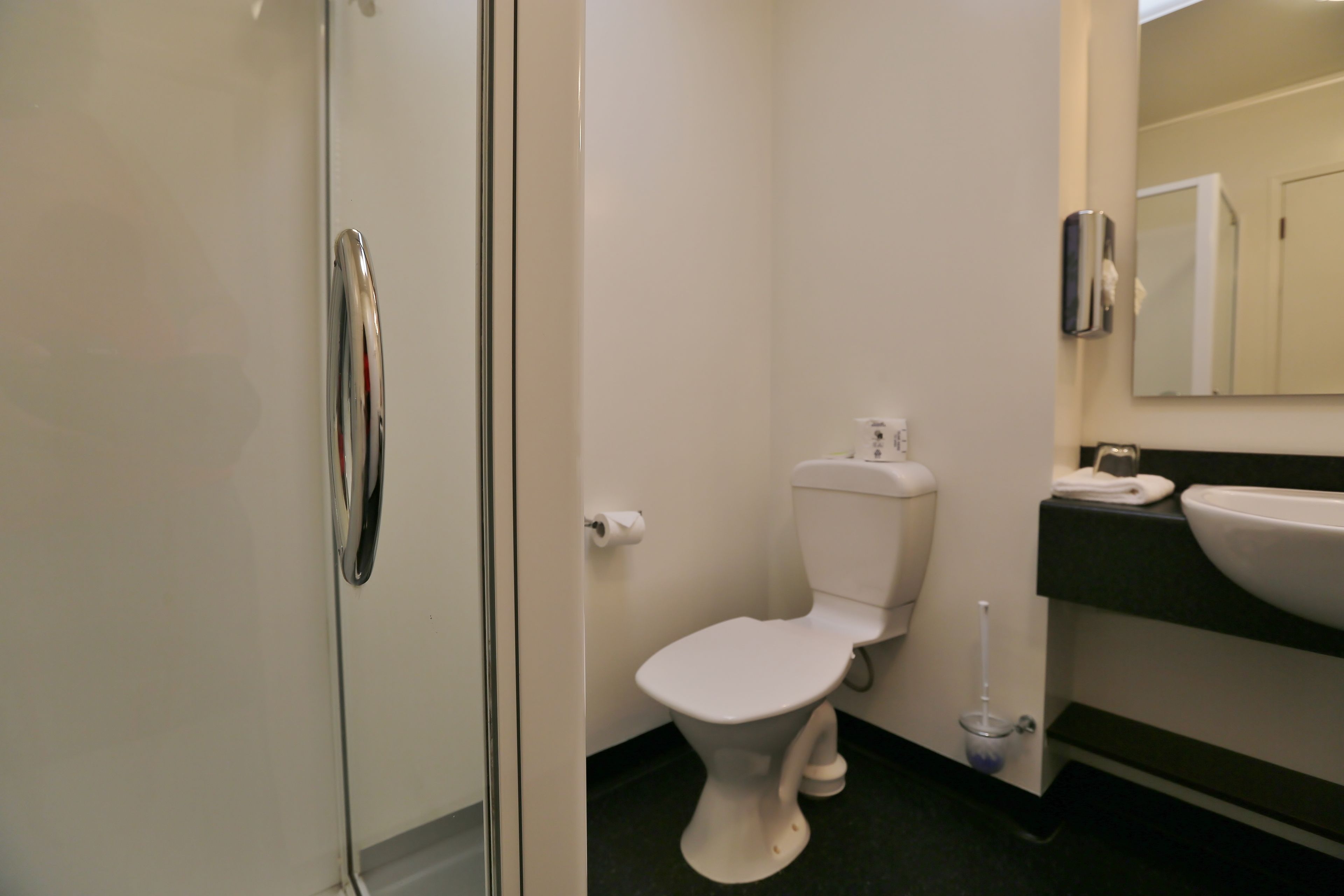 A bathroom with a toilet, sink, and hand dryer.