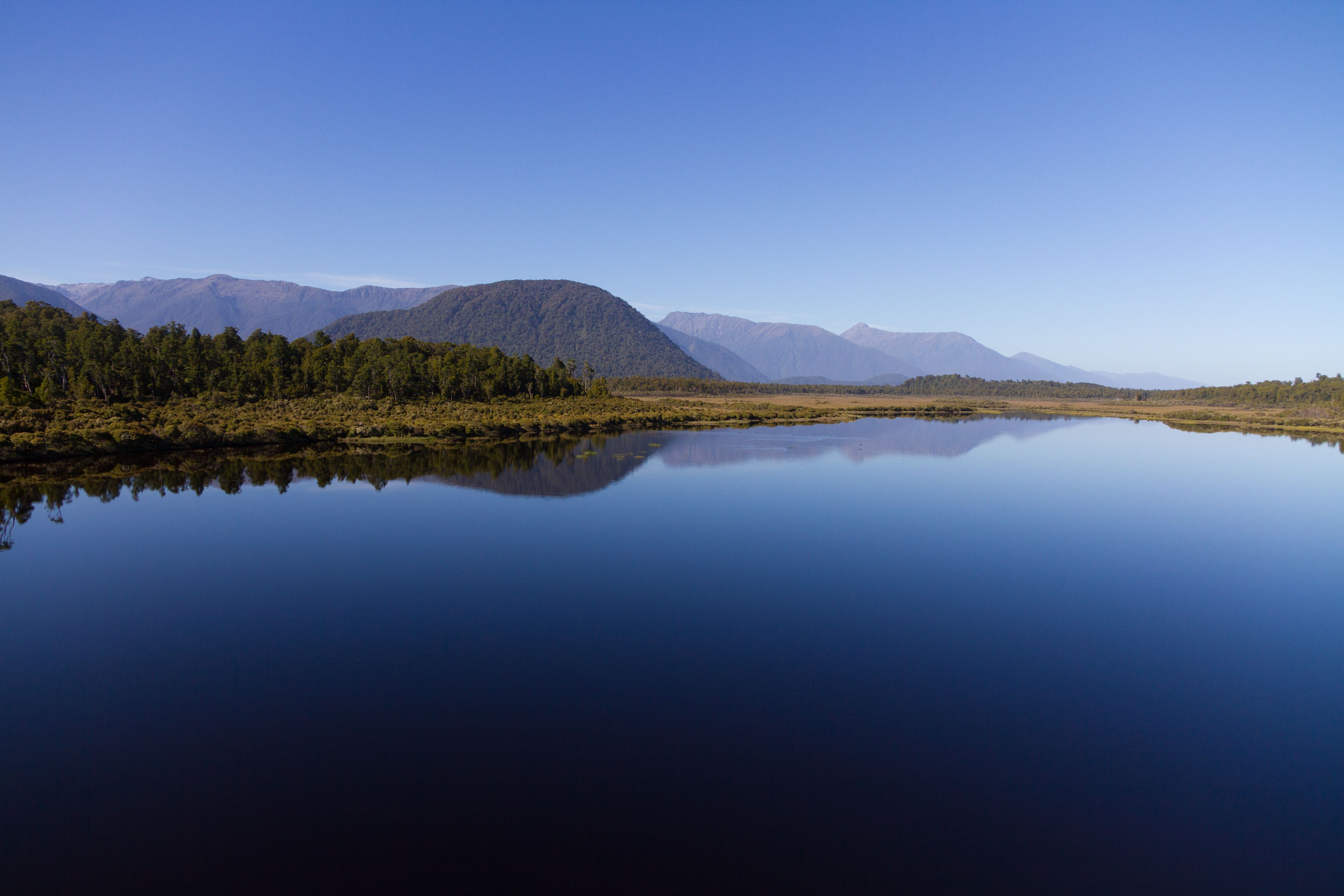 Un lago tranquilo que refleja montañas y árboles.