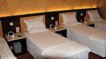 Cozy hotel room with single beds, dark wood headboards, and a small table for personal items.