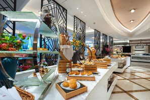 Un buffet proposant une variété de plats et agrémenté d’éléments décoratifs, le tout dans un cadre d’hôtel moderne.