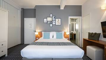 A hotel room with a large bed, bedside tables, a flat-screen TV, and a wall with framed pictures.