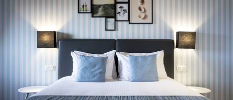 Habitación de hotel impecable con una cama grande, dos mesitas de noche y una pared decorada con cuadros y apliques.