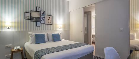 Una habitación de hotel con cama, lámparas de noche, una mesita y una silla.