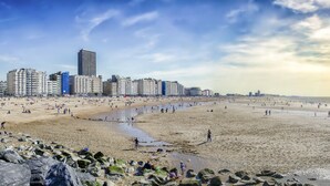 A beach with a city skyline in the background, featuring high-rise buildings and a clear sky. - Leopold Hotel Ostend (Ostend)