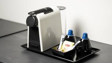 A coffee machine with a tray containing a Lipton tea bag, a yellow label, and two bottles.