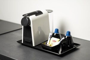 A coffee machine with a tray containing a Lipton tea bag, a yellow label, and two bottles.
