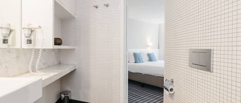 A modern bathroom with a marble countertop, a white sink, a trash bin, and a toilet.