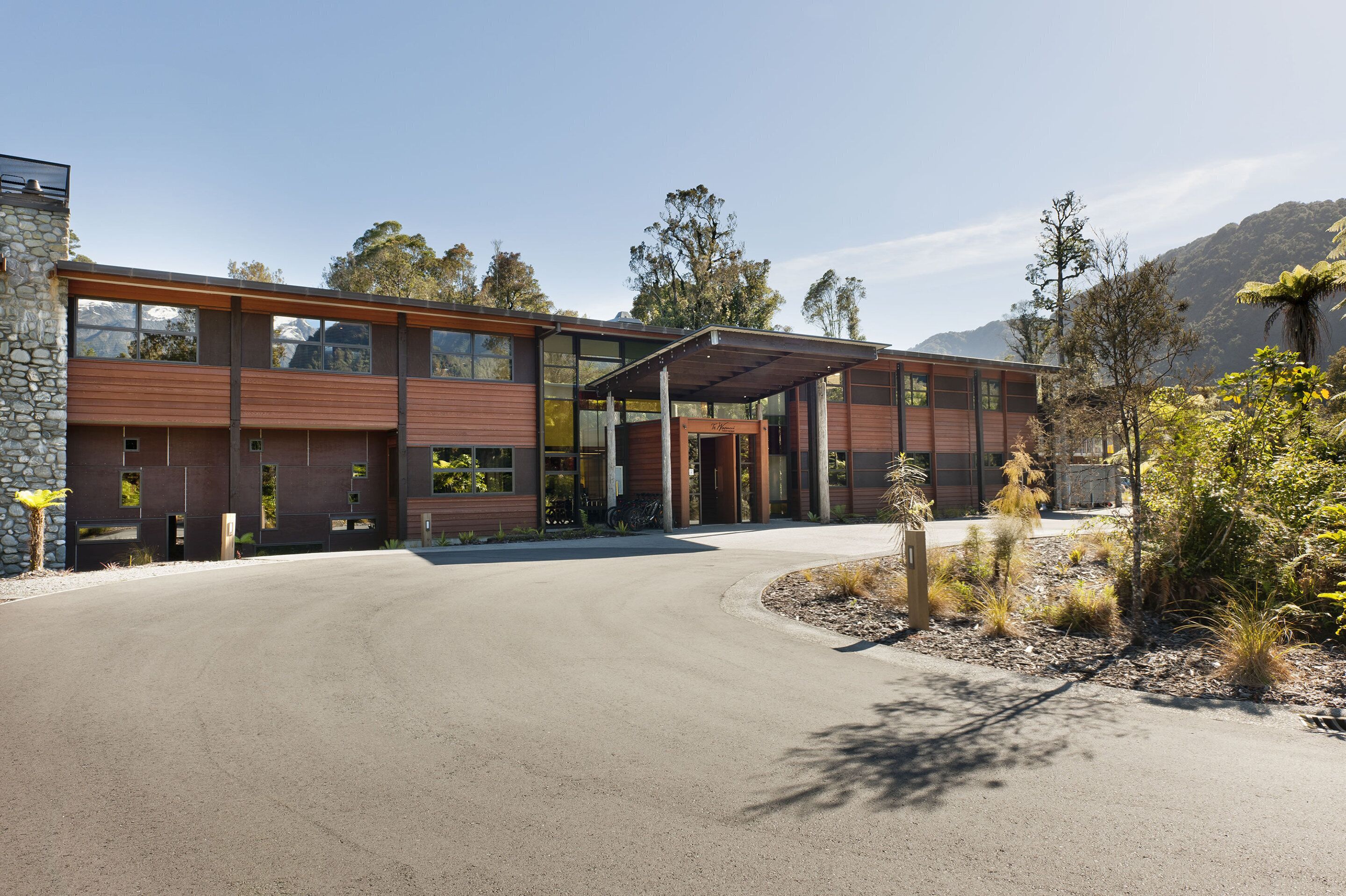 A modern building with a stone facade, large windows, and a covered entrance.
