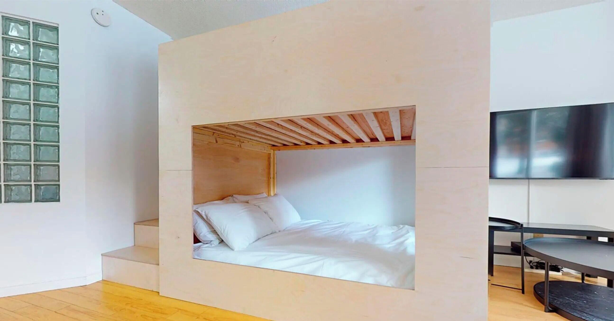 A minimalist room with a bed, a small table, and a TV.