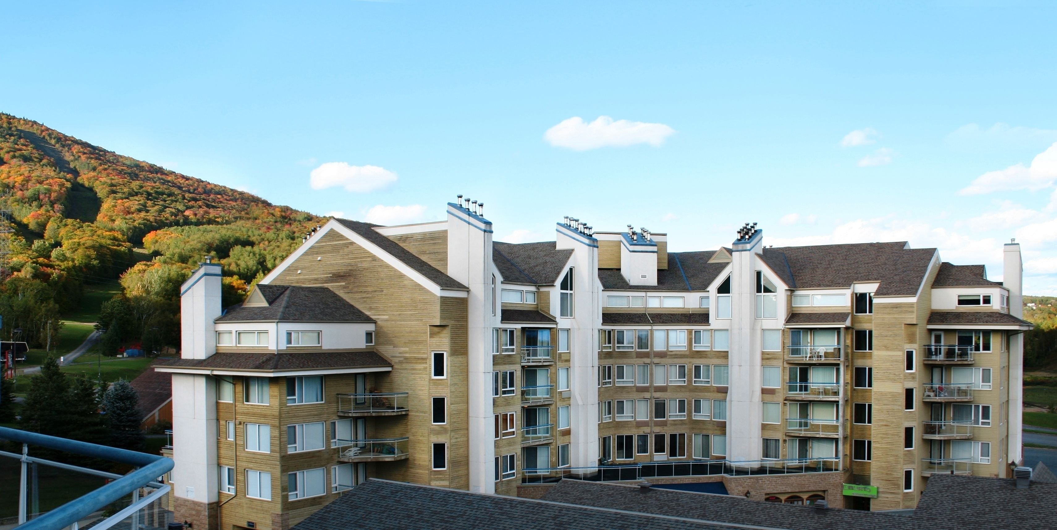 Een hotel met meerdere verdiepingen, met een modern architectuurontwerp, balkons en grote ramen.
