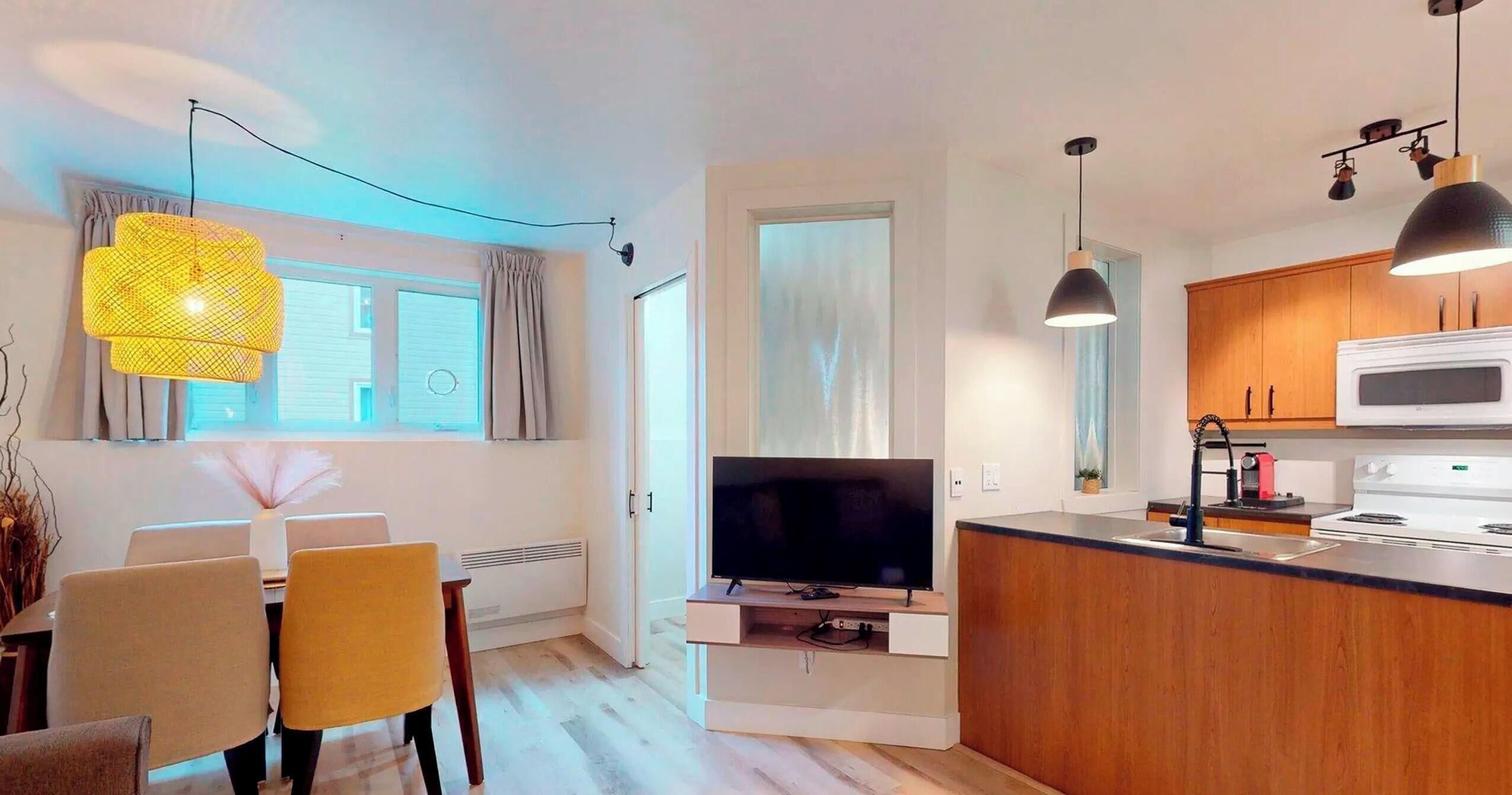 Eine moderne Küche mit Flachbildfernseher, Holzschränken und Pendelleuchten.
