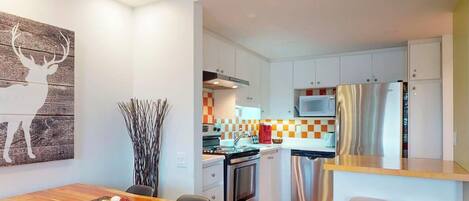 A modern kitchen with white cabinets, a stainless steel refrigerator, and a microwave.