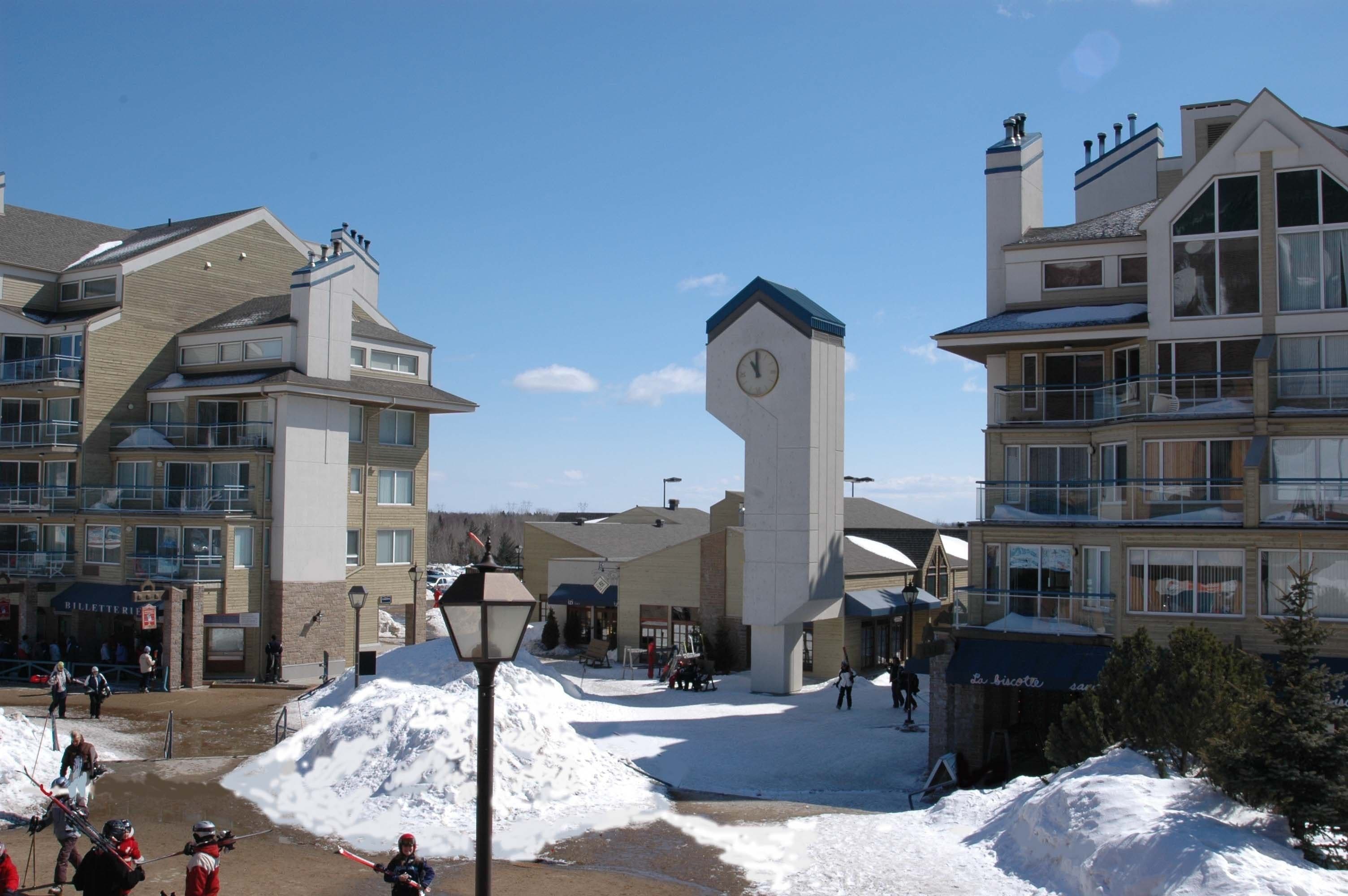 Un hotel con una imponente torre de reloj, varios balcones y una zona de pistas de esquí.