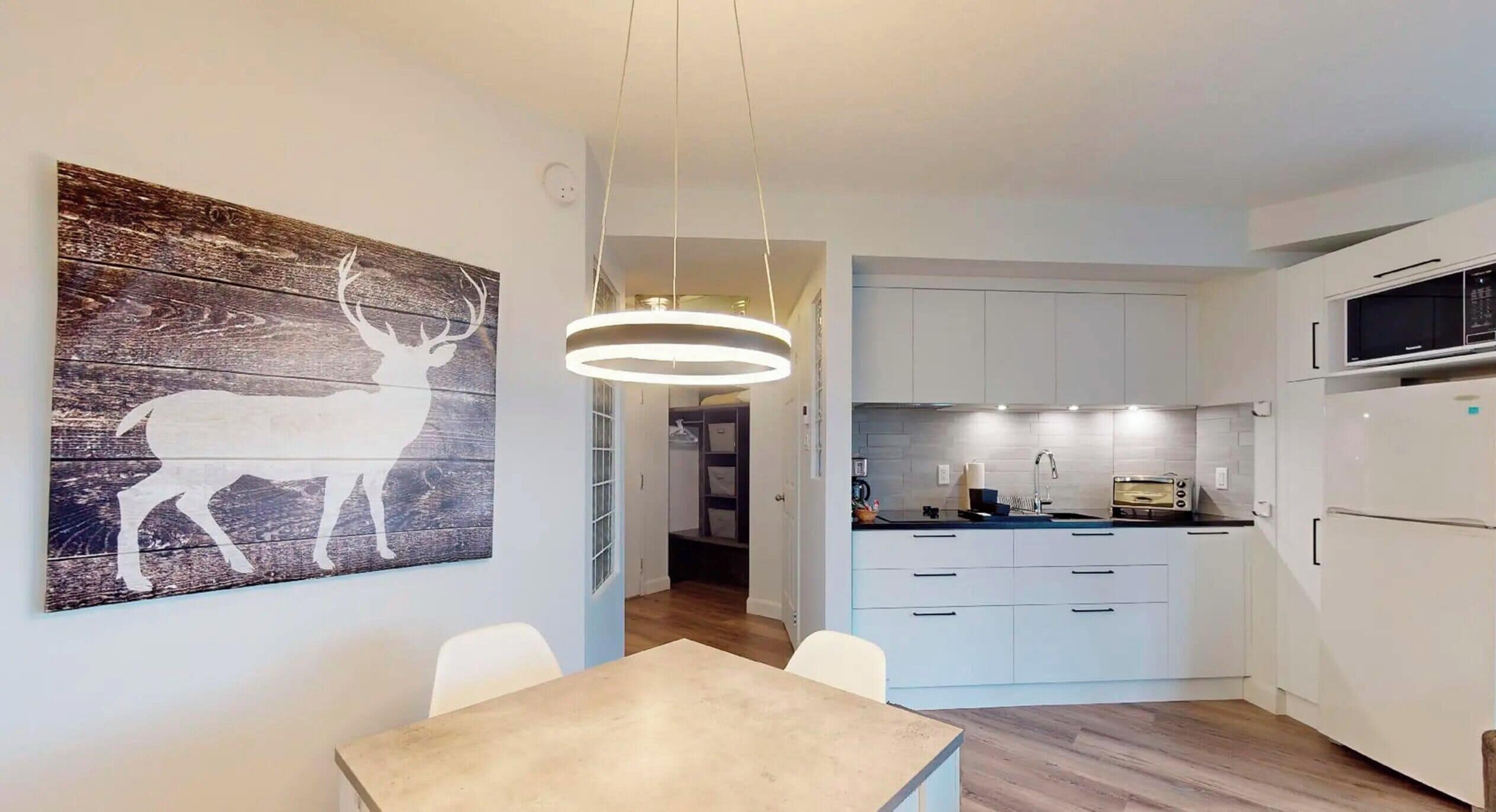 A modern kitchen with white cabinets, a built-in microwave, and a toaster.
