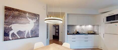 A modern kitchen with white cabinets, a built-in microwave, and a toaster.