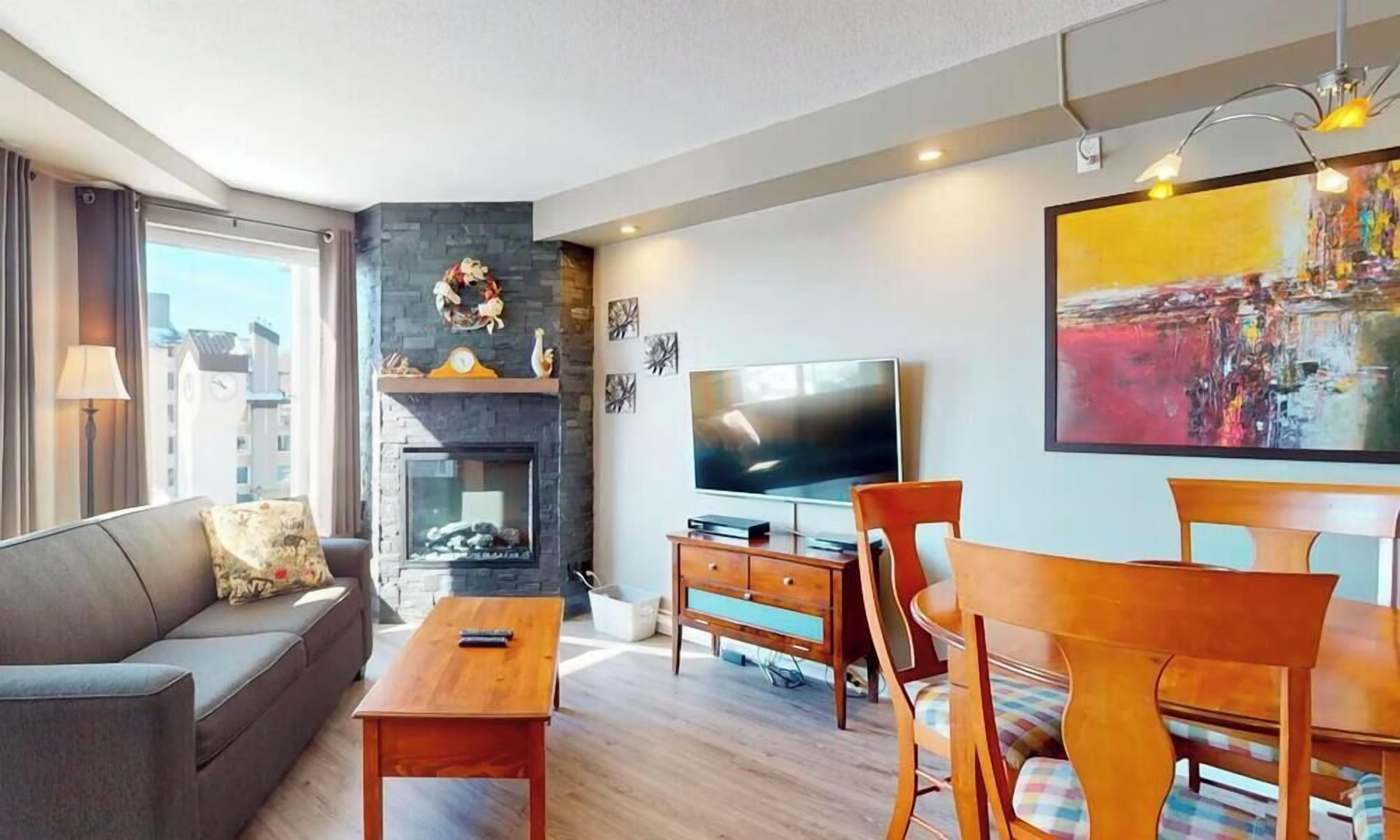 Un salon moderne doté d’une cheminée, d’un téléviseur à écran plat et d’un coin repas avec des meubles en bois.