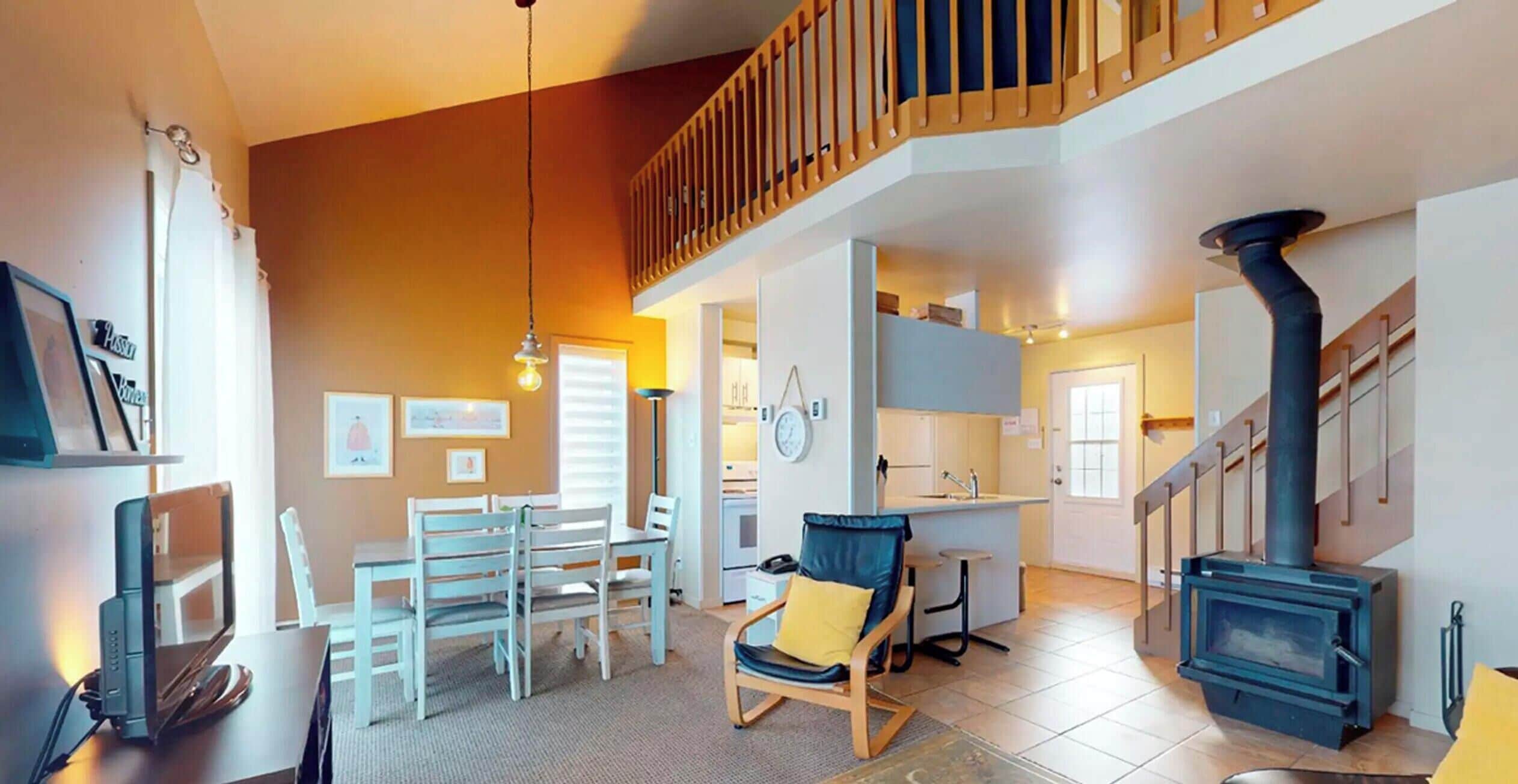 A spacious living area with a dining table, chairs, a sofa, a fireplace, and a staircase.