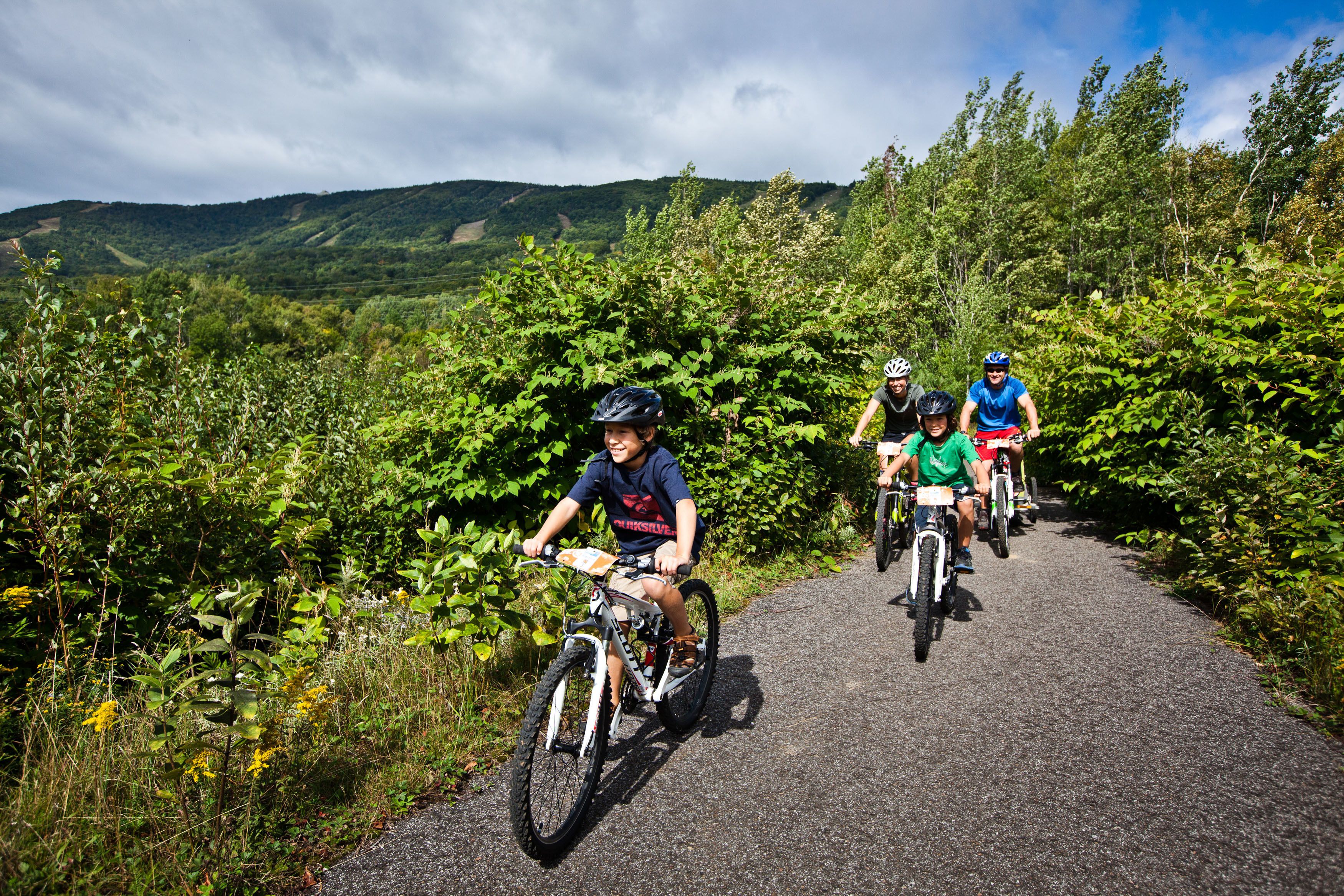 En gruppe mennesker cykler på en sti omgivet af grønt.