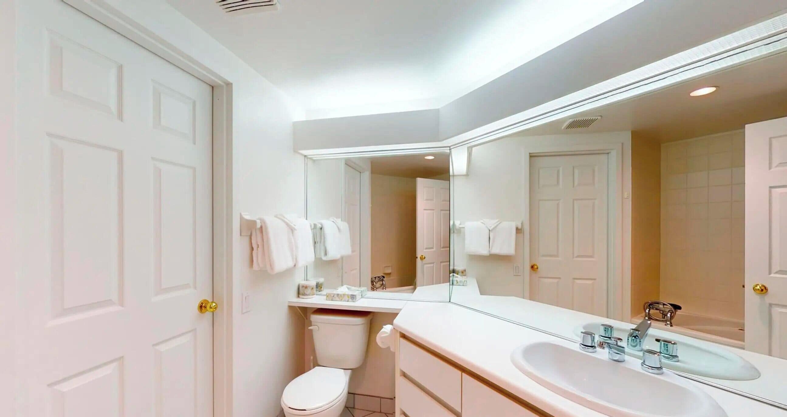 Un baño moderno con un lavamanos blanco, un inodoro y un espejo grande.
