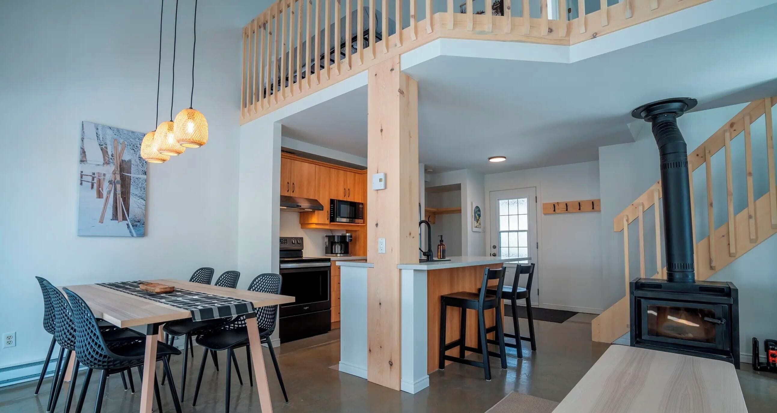A modern kitchen with wooden cabinets, a dining area with a table and chairs, and a wood-burning stove.