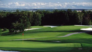 A golf course with sand bunkers, a flagstick, and a clear sky. - Hébergement Mont-Sainte-Anne (Beaupre)