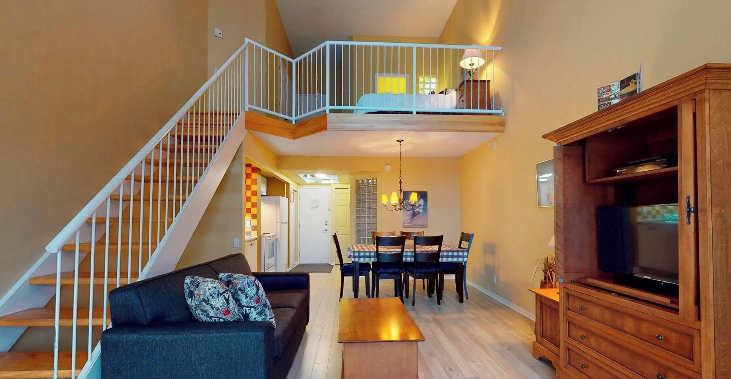 A multi-level living space with a staircase, a dining area, and a television.