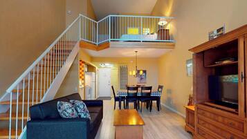 A multi-level living space with a staircase, a dining area, and a television.