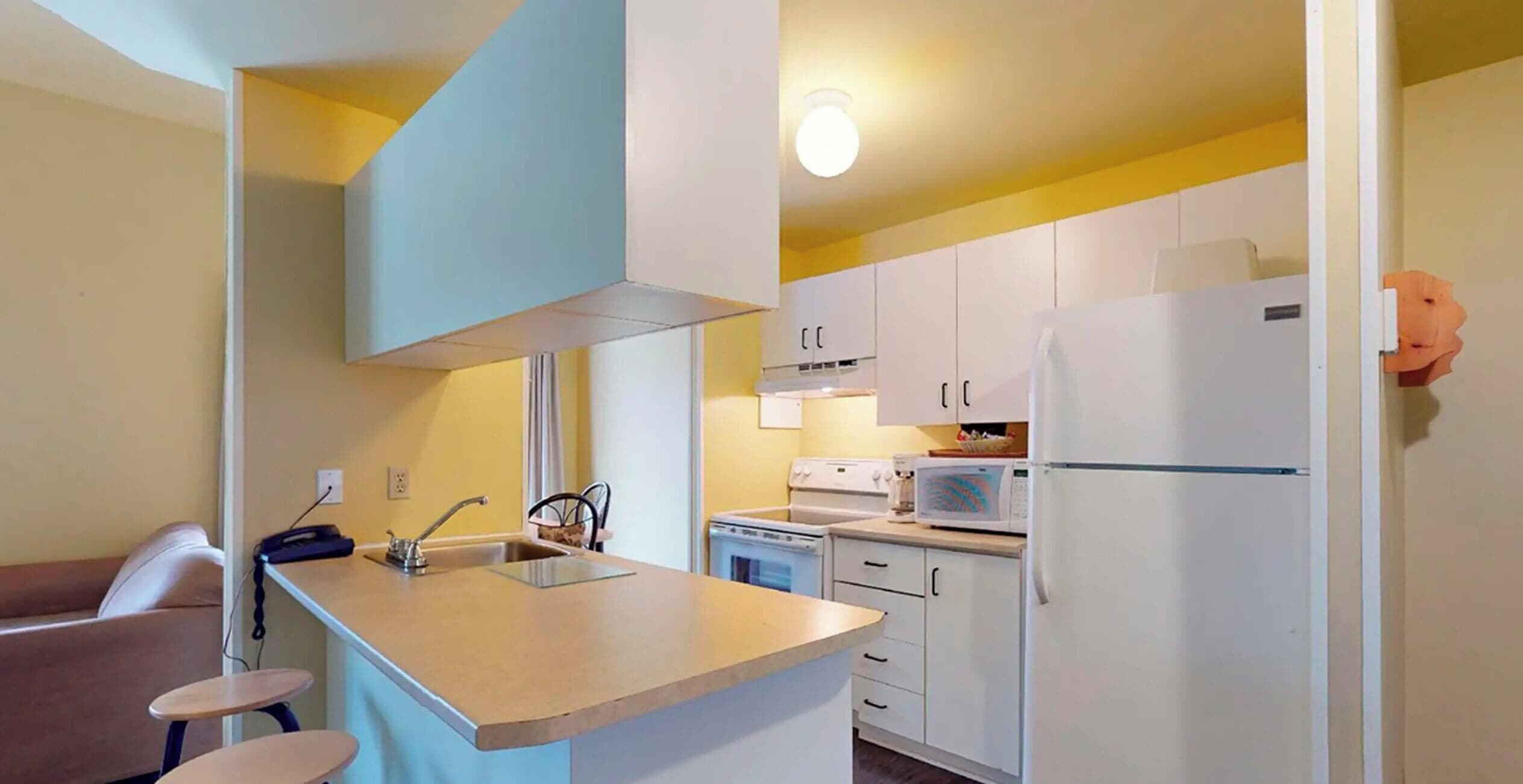 A compact kitchen with a sink, stove, microwave, and refrigerator.