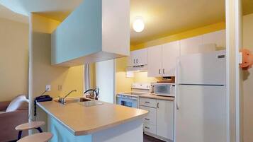 A compact kitchen with a sink, stove, microwave, and refrigerator.
