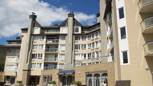 A multi-story hotel with a central courtyard, balconies, and a sign for 'Information & Hébergement'. - Hébergement Mont-Sainte-Anne (Beaupre)