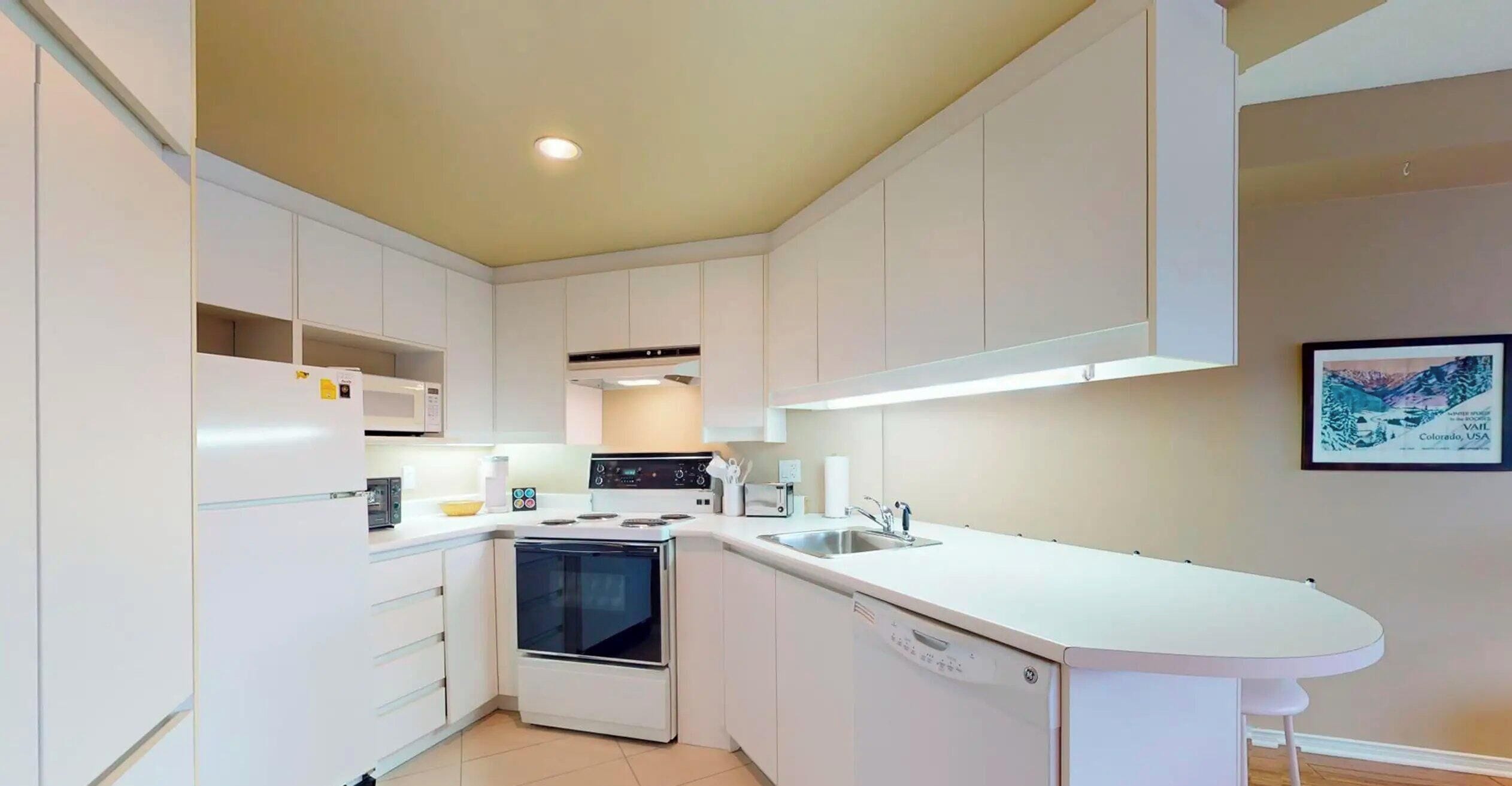 A modern kitchen with white cabinetry, a built-in oven, a dishwasher, and a stainless steel sink.
