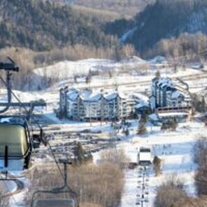 A ski resort with multiple buildings, a ski lift, and snow-covered terrain. - Hébergement Mont-Sainte-Anne (Beaupre)