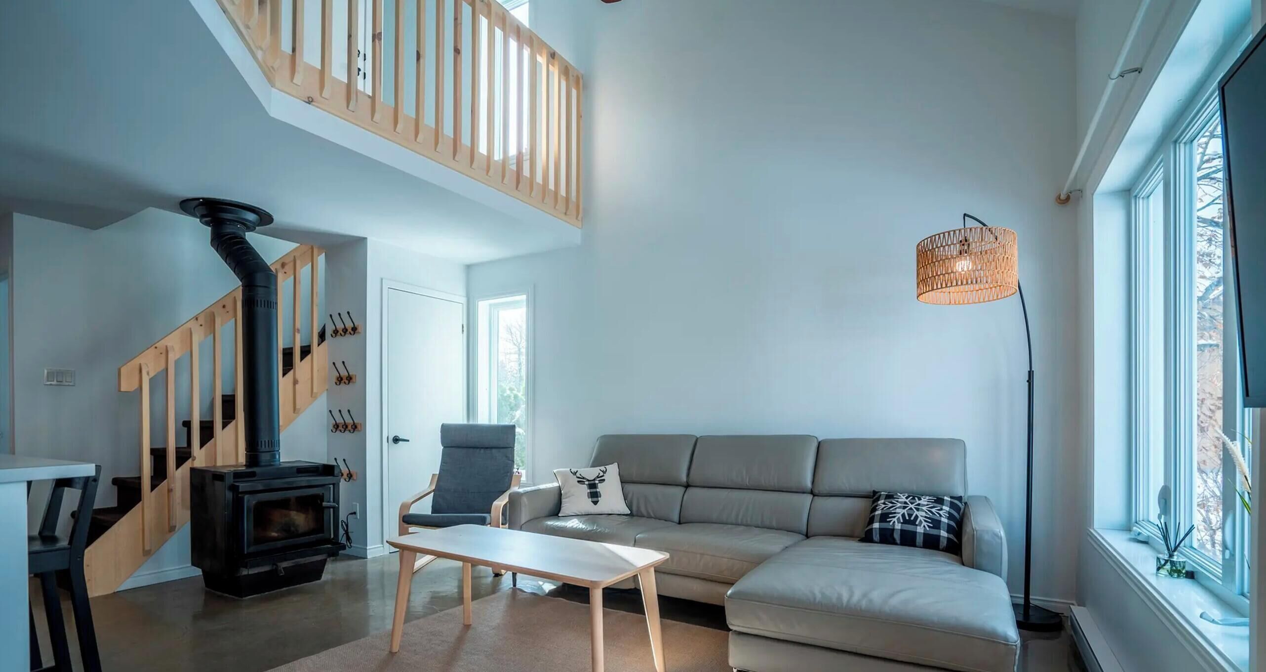 A modern living room with a built-in wood-burning stove, a sofa, a dining table, and a staircase.