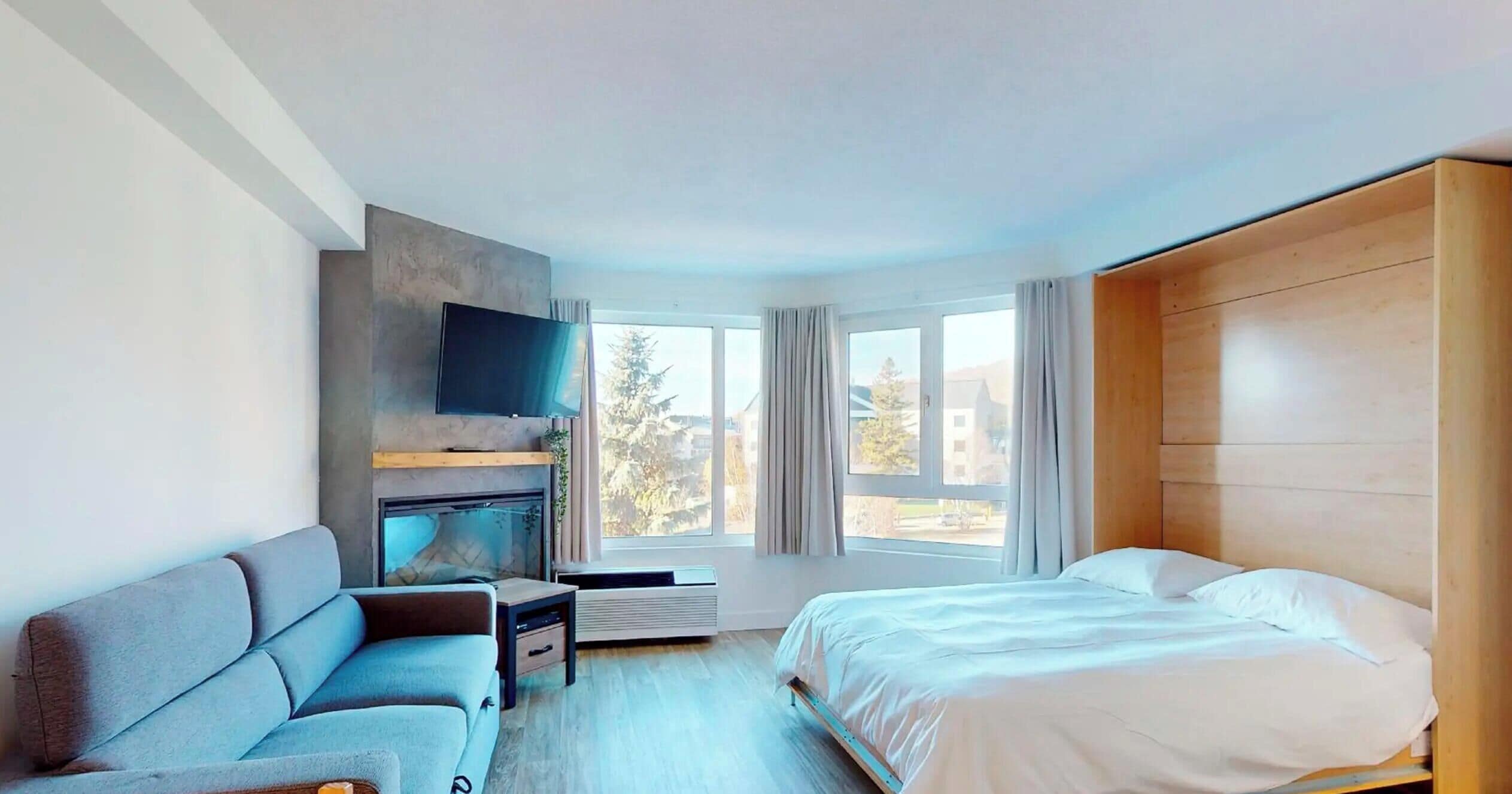 Une chambre d’hôtel moderne équipée d’un lit, d’un canapé, d’une télévision et d’une cheminée.