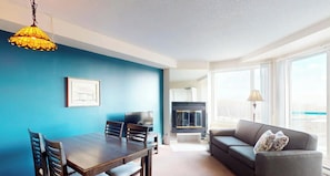 A modern living room with a dining area, a sofa, a TV, and a fireplace. - Hébergement Mont-Sainte-Anne (Beaupre)