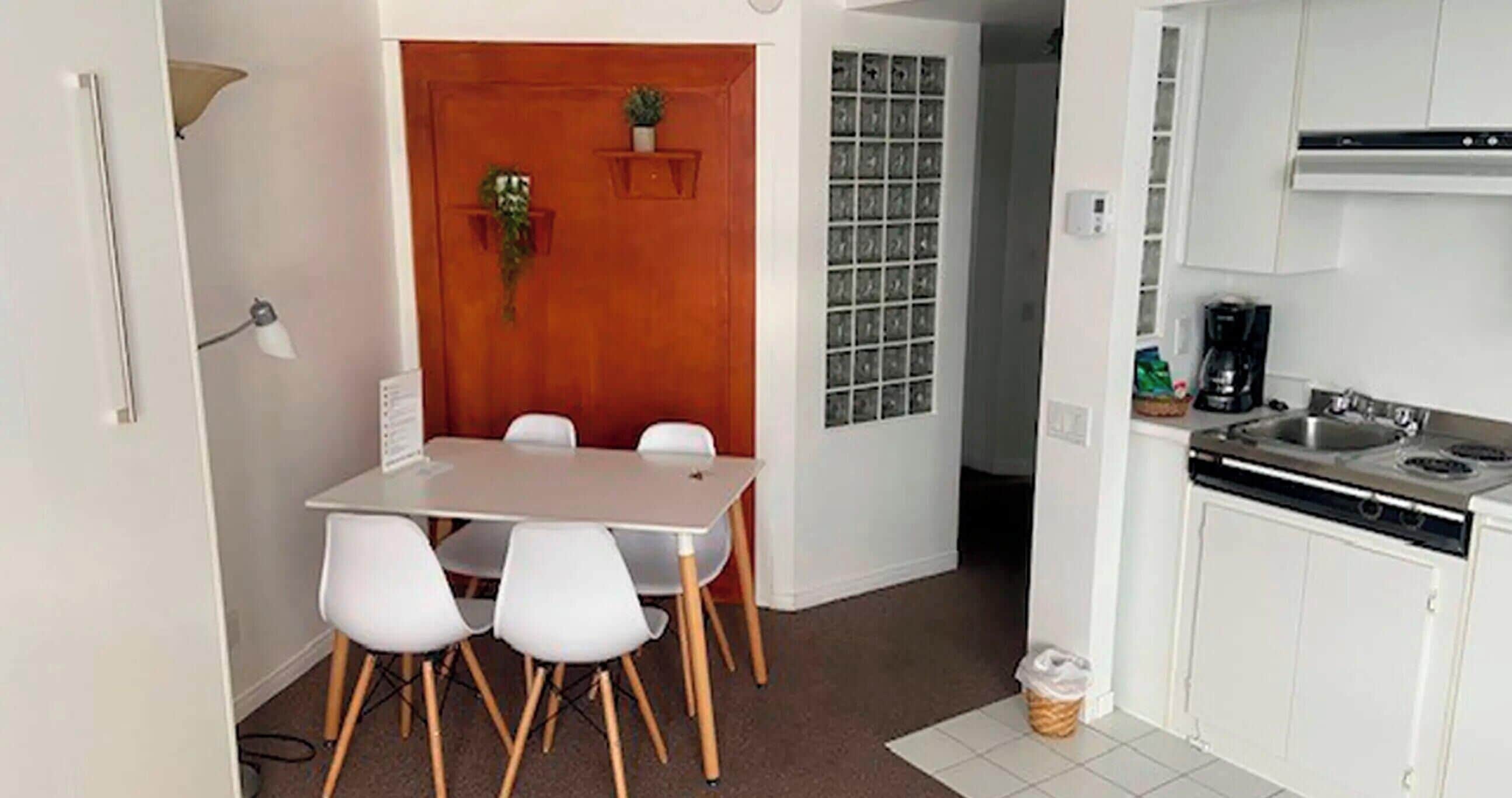 A compact kitchen with a dining area, a coffee machine, and a trash bin.