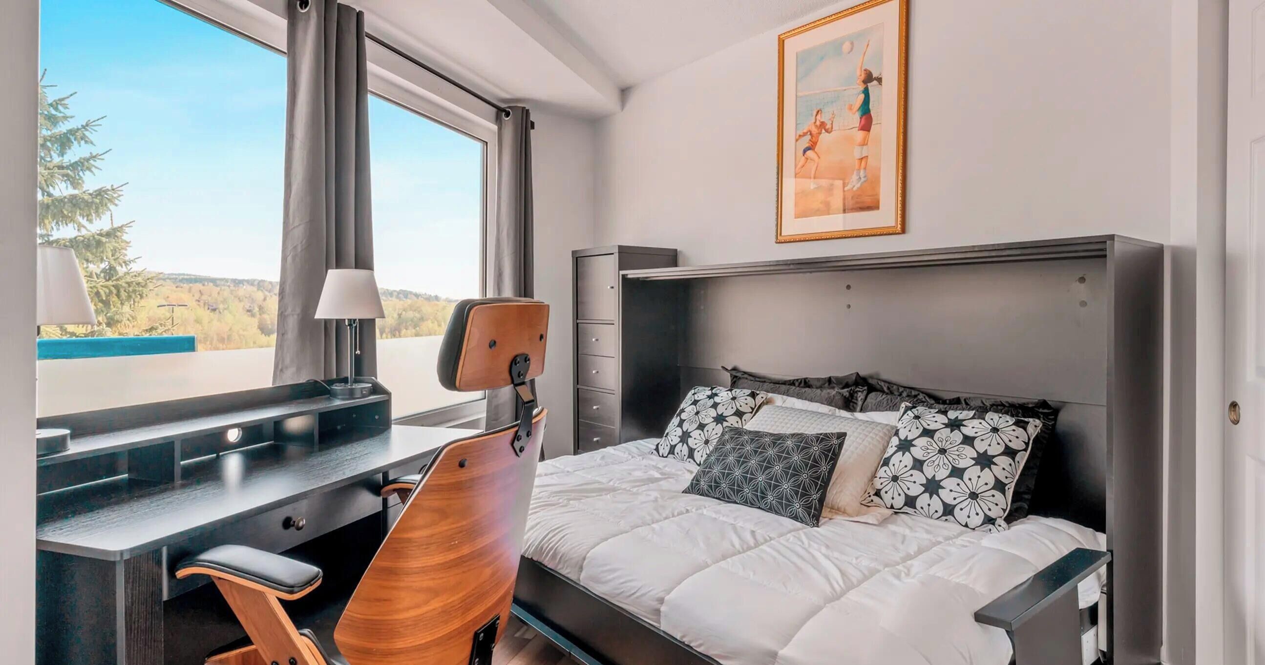 Habitación de hotel con cama, escritorio, silla y ventana con vistas.