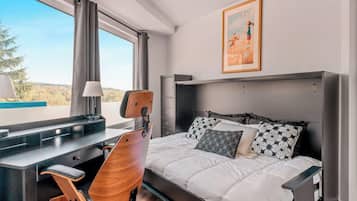 Habitación de hotel con cama, escritorio, silla y ventana con vistas.