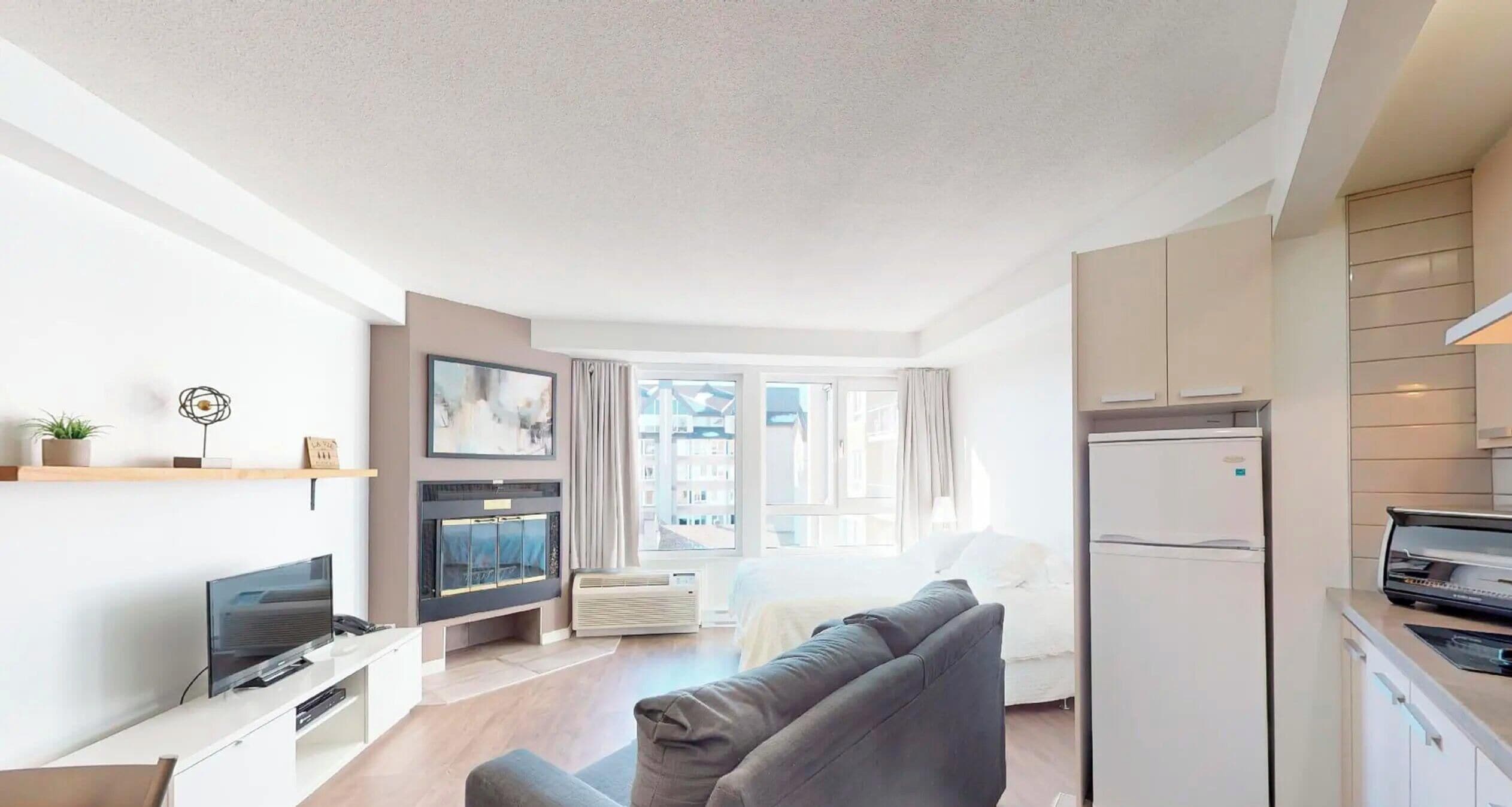 A modern apartment with a living room, kitchen, and a large window.