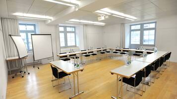 Une salle de conférence avec une longue table, des chaises, un tableau blanc et des fenêtres.