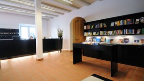 Una biblioteca con estanterías, un mostrador de recepción y una planta en maceta.