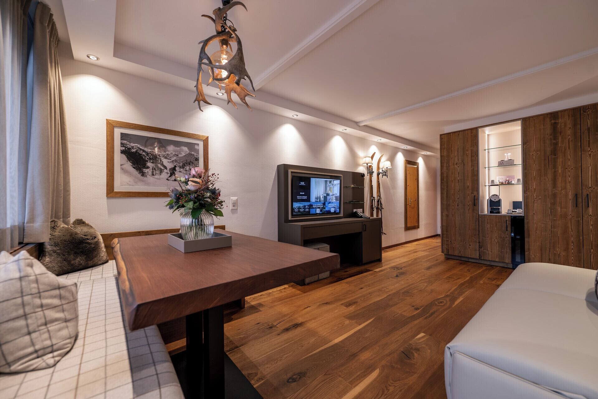 A modern living room with a wooden floor, a dining table, a sofa, a TV, and a fireplace.