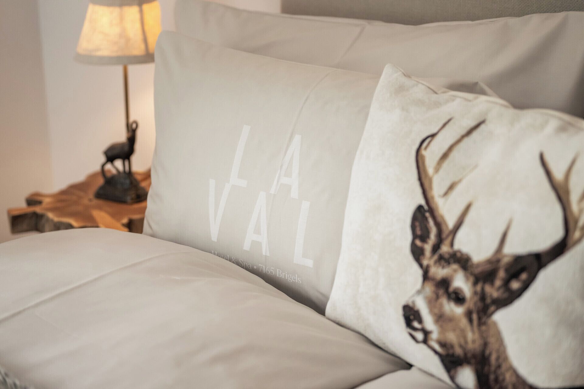 A sofa with a pillow featuring a deer and the text "LA VAL."