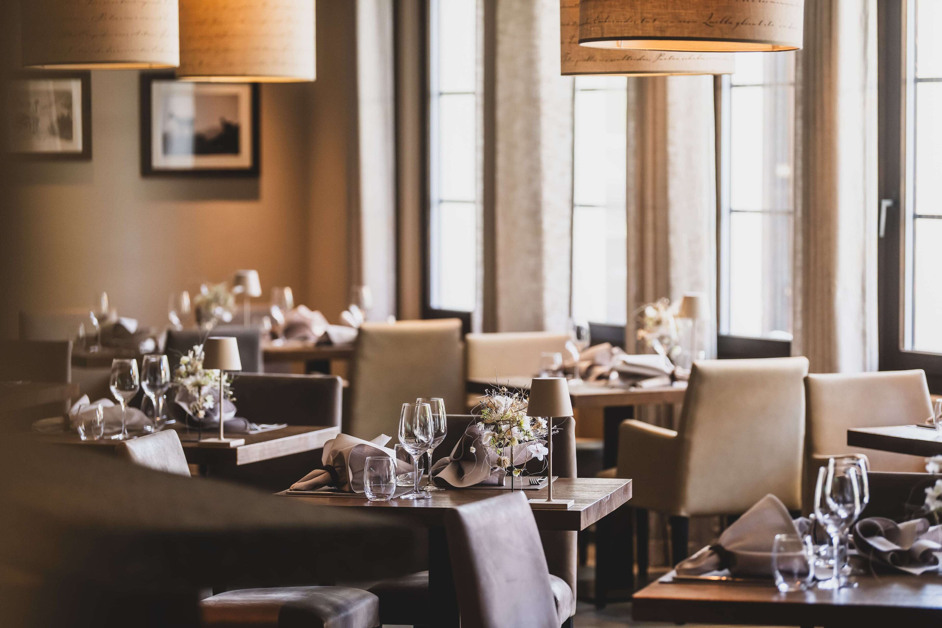 A restaurant with multiple tables set for dining, featuring candles and floral centerpieces.