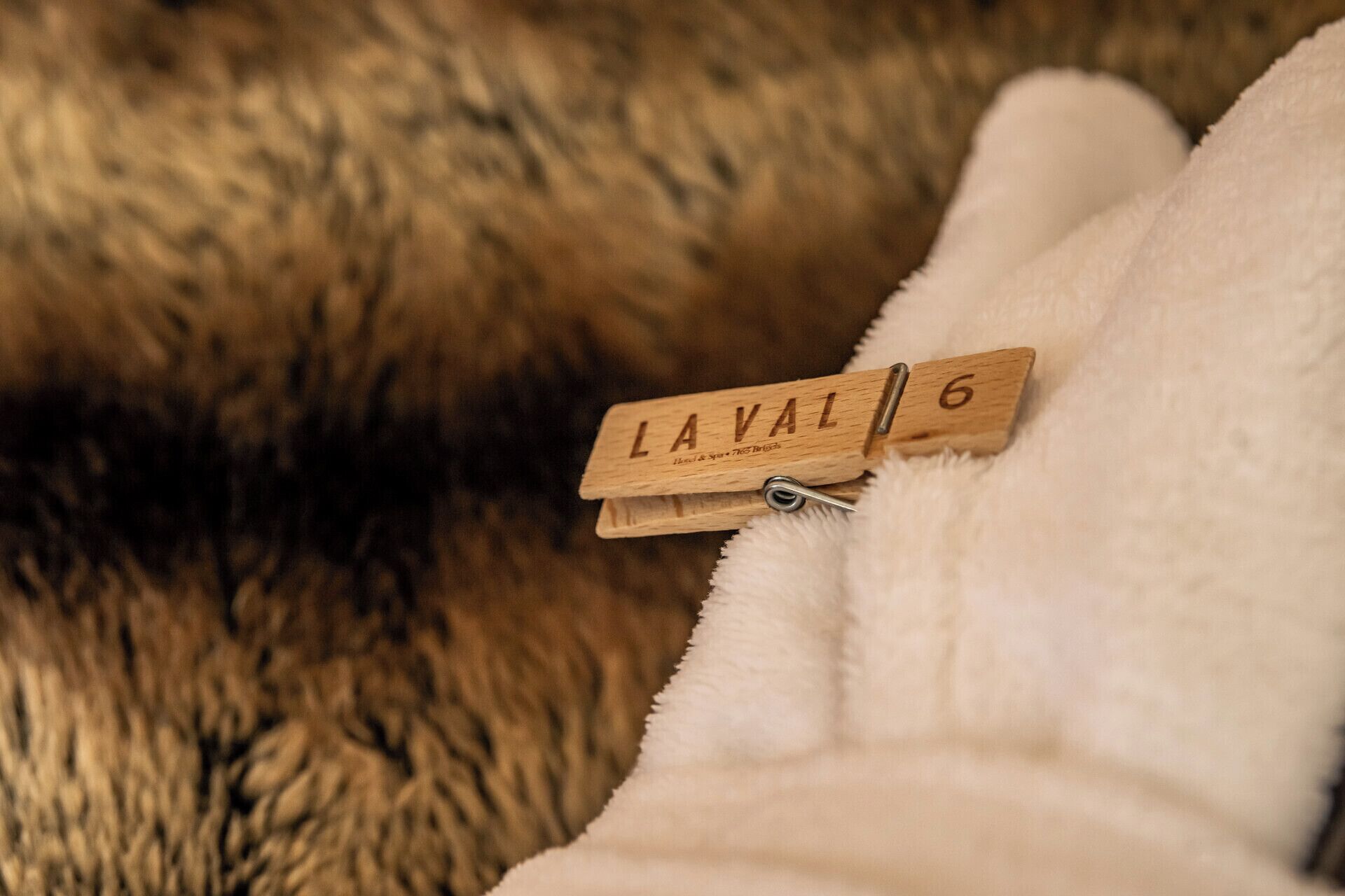 A wooden clothespin with the word "LAVAL" and the number "6" on it, placed on a fluffy white surface.