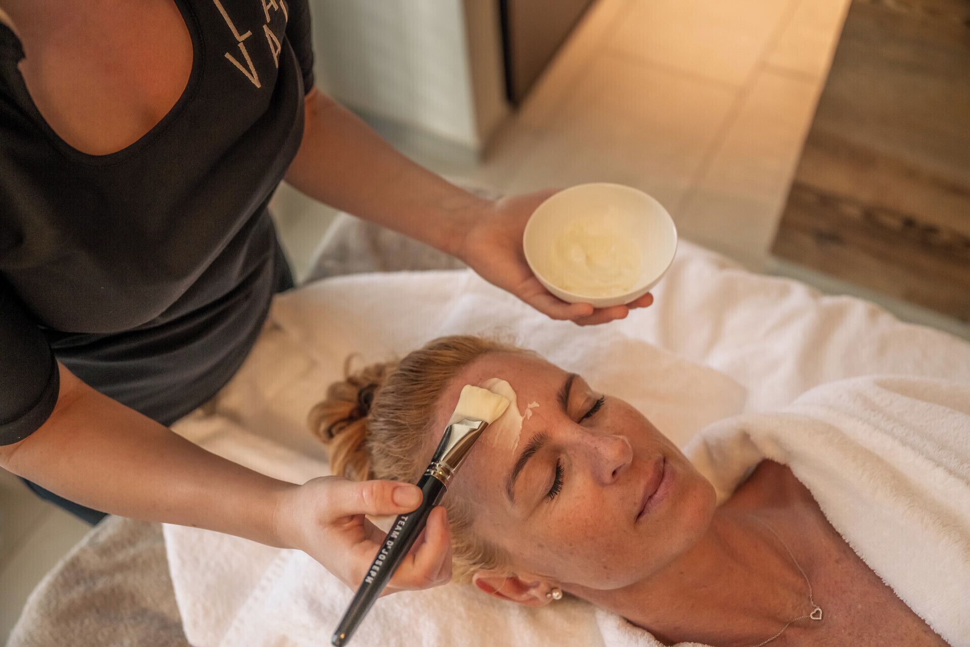 A person receiving a facial treatment with a cream.